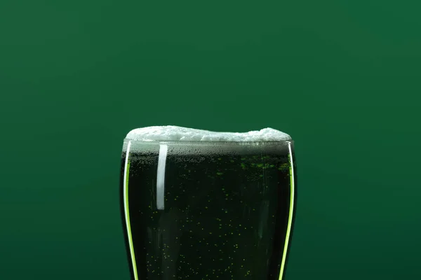 Стакан пива с пеной, изолированной на зеленом с копировальным пространством, концепция дня Святого Патрика — стоковое фото