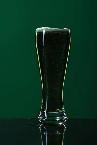 Стакан пива с пеной изолирован на зеленой концепции дня Святого Патрика — стоковое фото