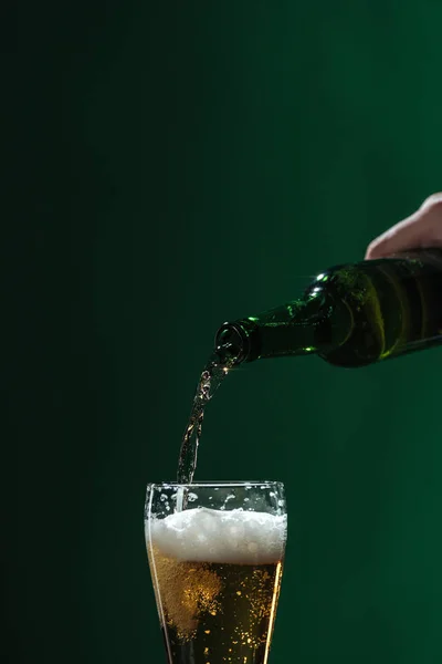 Лиття пива в склянку з піною ізольовано на зеленому, концепція святкового дня — стокове фото
