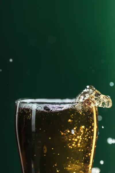 Glass of beer with splashes isolated on green with copy space, isolated on green — Stock Photo