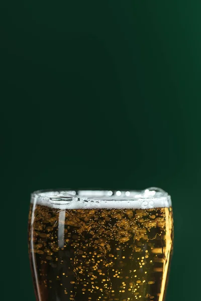 Закрытие пивного стакана с пеной и пузырьками, изолированными на зеленой концепции дня Святого Патрика — стоковое фото