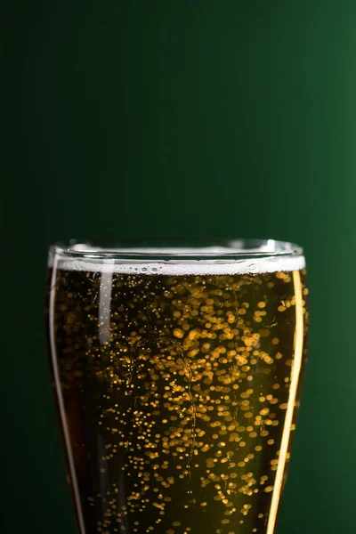 Primo piano di vetro di birra con schiuma e bolle isolato sul verde, concetto giorno di San Patrizio — Foto stock