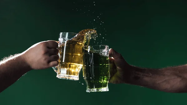 Teilansicht von Männern, die Biergläser mit Spritzern klappern, isoliert auf dunkelgrünem, patrick day Konzept — Stockfoto