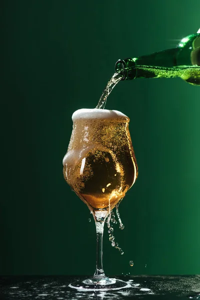 Pouring beer into glass with splashes and foam isolated on green, st patrick day concept — Stock Photo