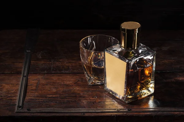 Пляшка з порожньою етикеткою і склянкою віскі на коричневому дерев'яному столі — стокове фото