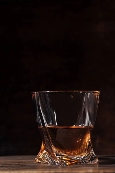 Vista de cerca de whisky en vidrio sobre mesa de madera en negro - foto de stock