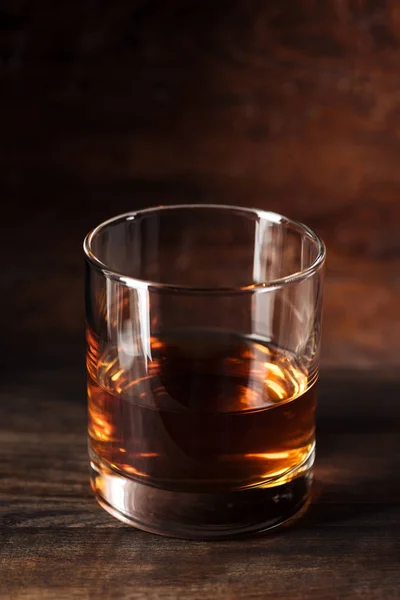 Vista de cerca del vaso de alcohol ámbar de lujo en la mesa de madera - foto de stock