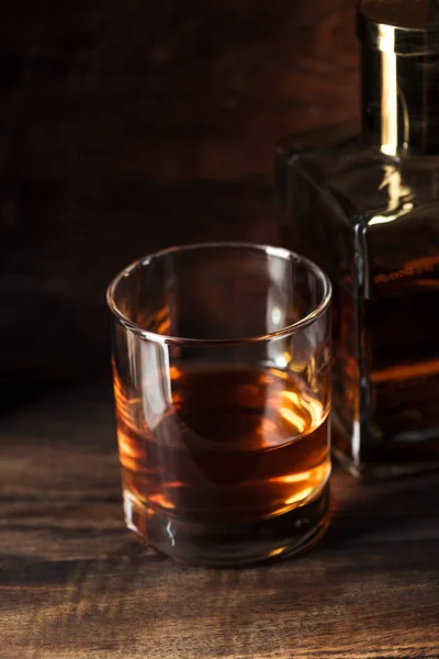 Close-up view of glass of bourbon and bottle on wooden table — Stock Photo