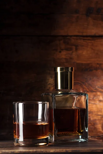 Close-up view of glass of brandy and bottle on wooden table — Stock Photo