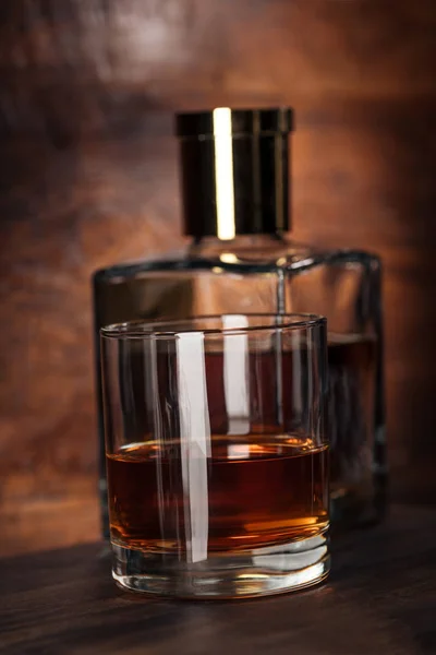 Vue rapprochée sur verre de cognac et bouteille sur table en bois — Photo de stock