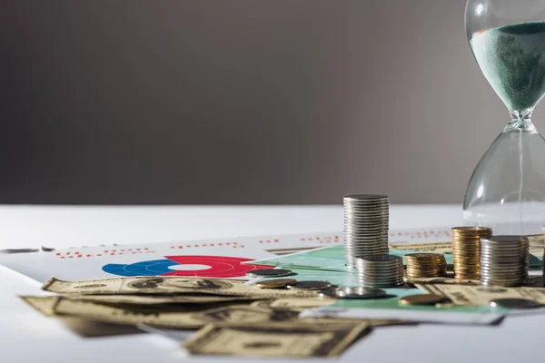 Enfoque selectivo de las pilas de monedas, reloj de arena en dólares y billetes en euros - foto de stock