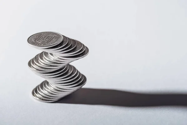 Pila de monedas de plata ucranianas y sombra sobre fondo gris - foto de stock