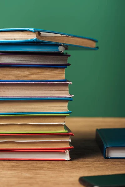 Foco seletivo de pilha com livros sobre mesa de madeira e fundo verde — Fotografia de Stock