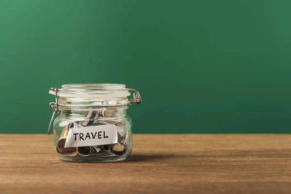 Glass jar with coins and lettering on wooden table and green background — Stock Photo