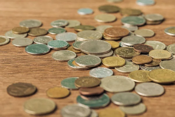 Foco seletivo de diferentes moedas colocadas em fundo embaçado de madeira — Fotografia de Stock