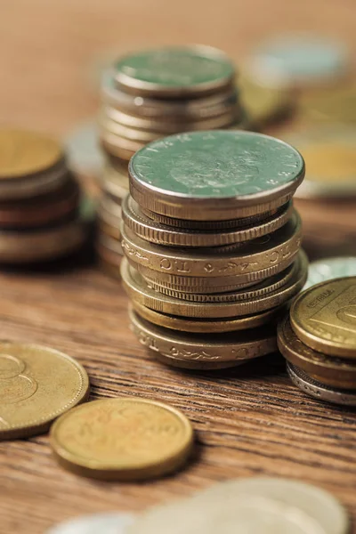 Enfoque selectivo de pilas con diferentes monedas sobre fondo de madera - foto de stock