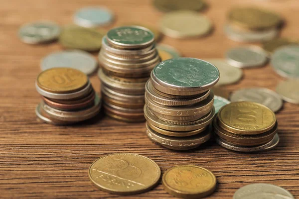 Enfoque selectivo de las pilas de monedas sobre fondo de madera y borrosa - foto de stock