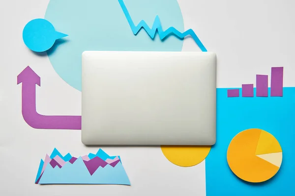 Draufsicht auf geschlossenen Laptop mit Papierdiagramm und Diagrammen, Zeiger auf weißem Hintergrund — Stockfoto