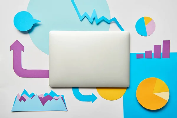 Vista superior de laptop fechado e gráficos de papel e gráficos, em fundo branco — Fotografia de Stock