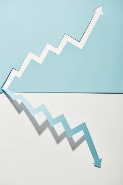 Vista superior de ponteiros de papel simétricos sobre fundo branco e azul — Fotografia de Stock