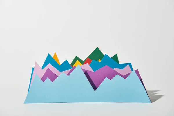Gráficos de papel azul, púrpura, verde, rojo y amarillo sobre fondo blanco - foto de stock