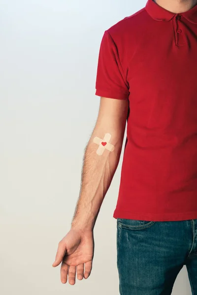 Vista parcial del paciente en camiseta roja con yeso, concepto de donación de sangre - foto de stock