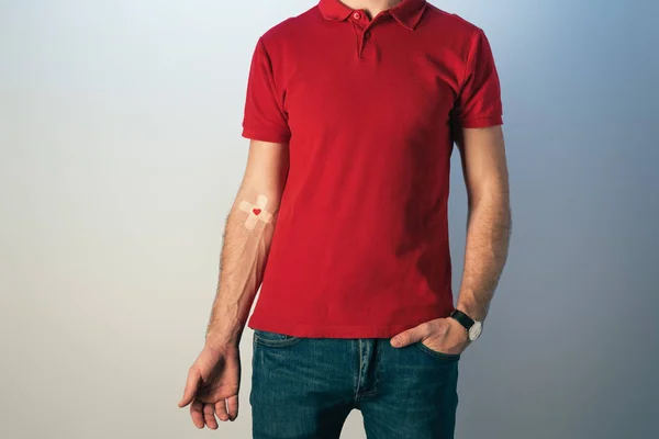 Cropped view of patient in red t-shirt and blue jeans with plasters, blood donation concept — Stock Photo