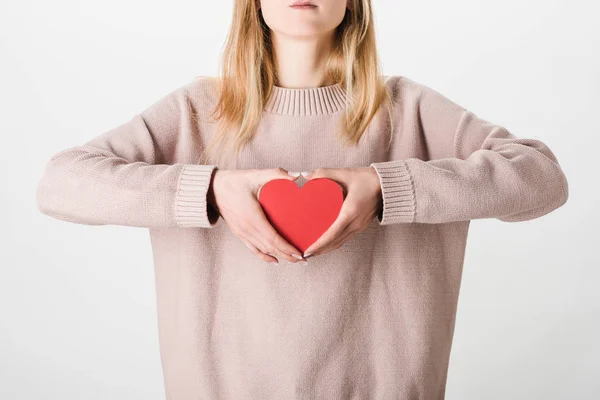 Частковий вигляд жінки в бежевому светрі, що тримає паперове серце на білому тлі — стокове фото