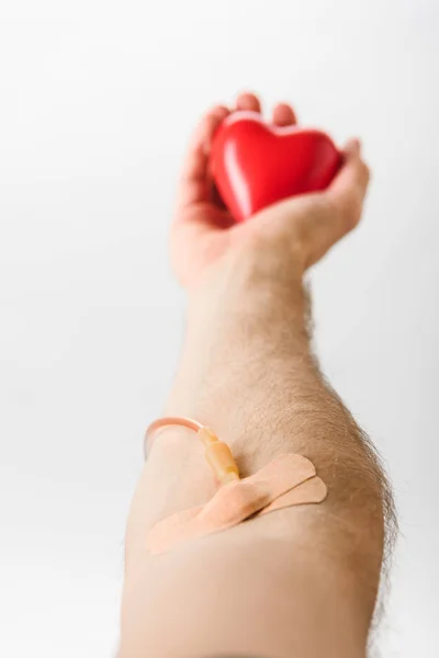 Ausgeschnittene Ansicht des Blutspenders mit Katheter und Pflaster mit Spielzeugherz, Blutspendekonzept — Stockfoto