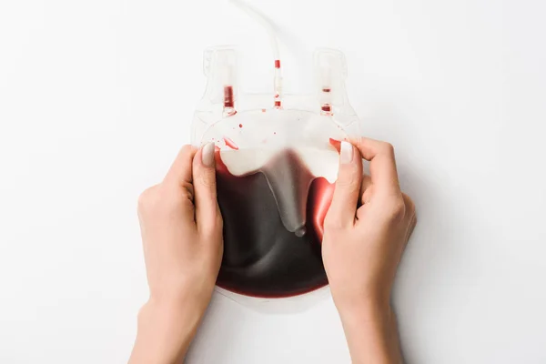 Partial view of woman holding drip with blood on white background, blood donation concept — Stock Photo