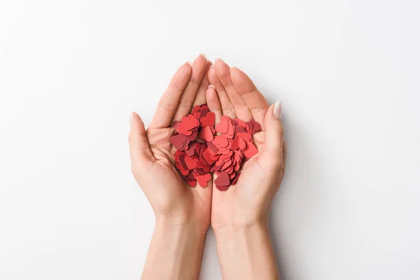 Vista recortada de la mujer sosteniendo corazones de papel sobre fondo blanco - foto de stock