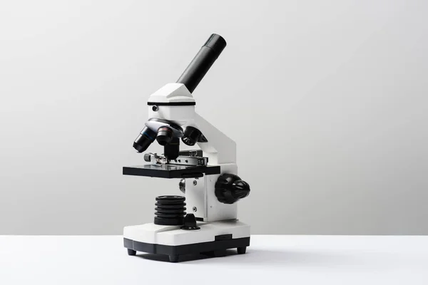 Microscópio em fundo cinza com espaço de cópia — Fotografia de Stock