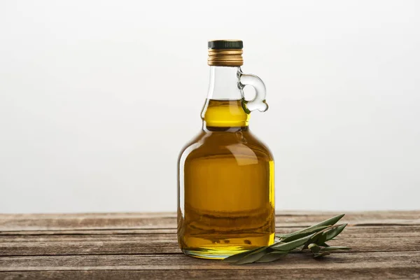 Flasche Olivenöl und Blätter des Olivenbaums isoliert auf grau — Stockfoto