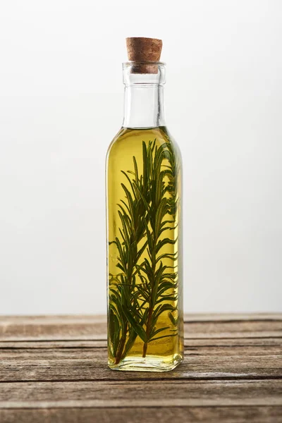 Bottle of flavored oil with rosemary branches on wooden surface — Stock Photo