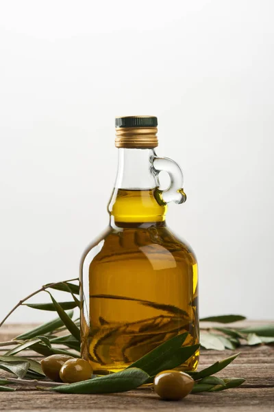 Botella de aceite con hojas de olivo y aceitunas aisladas en gris - foto de stock