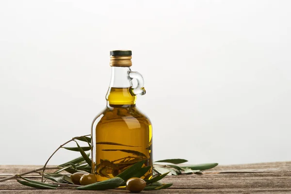 Botella de aceite con hojas de olivo y aceitunas aisladas en gris - foto de stock