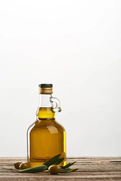 Botella de con hojas de olivo y aceitunas aisladas en gris - foto de stock