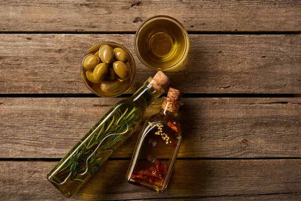 Draufsicht auf aromatisierte und Schalen mit Öl und Oliven auf Holzoberfläche — Stockfoto