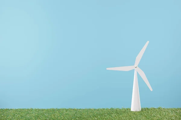 Modelo de molino de viento sobre hierba verde y fondo azul - foto de stock