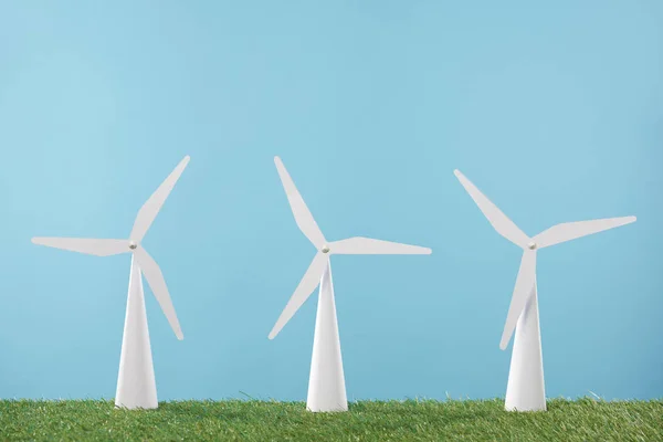 Weiße Windmühlenmodelle auf Gras und blauem Hintergrund — Stockfoto