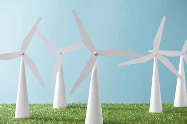 White windmill models on blue background and green grass — Stock Photo