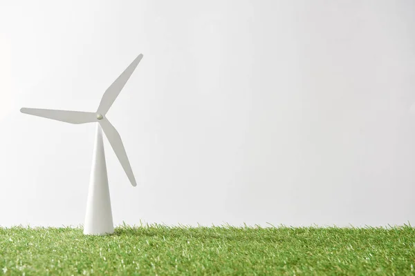 Modelo de molino de viento sobre hierba verde y fondo blanco con espacio de copia - foto de stock