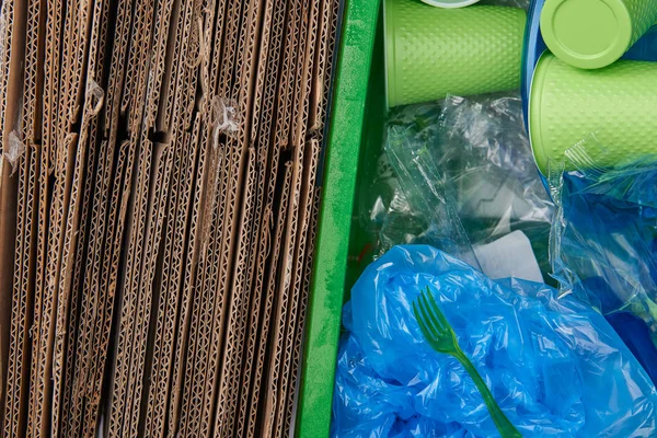 Вид сверху на мусор с картонными, скомканными пластиковыми пакетами, пластиковыми чашками и вилками — стоковое фото