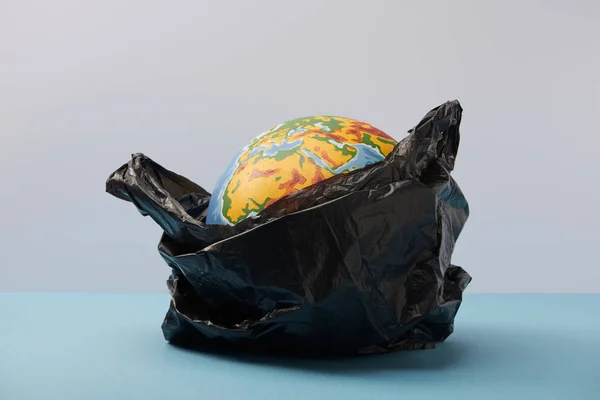 Globus in schwarzem Polyethylen-Beutel auf blauem Tisch und Hintergrund — Stockfoto