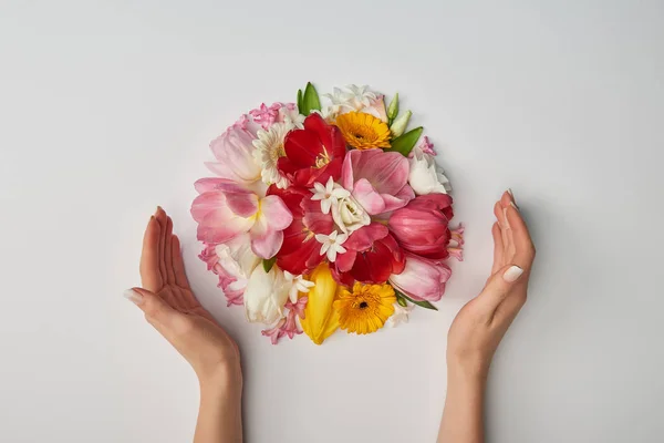 Vista recortada de las manos femeninas y ramo de flores sobre fondo blanco - foto de stock