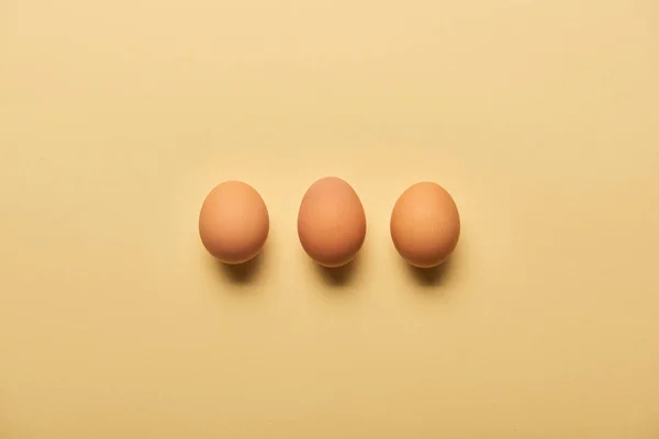 Flat lay with brown organic eggs arranged in row on yellow background — Stock Photo