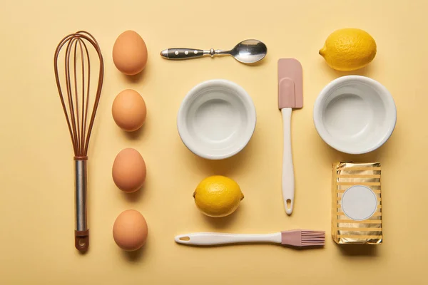 Плоский ліжко з посудом для приготування їжі, лимонами, маслом та яйцями на жовтому фоні — стокове фото