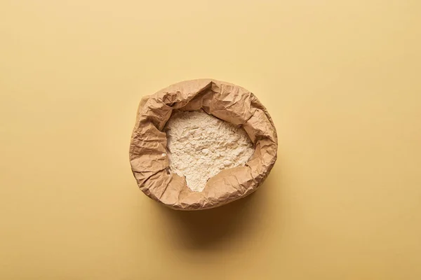 Top view of paper bag full of flour on yellow background — Stock Photo