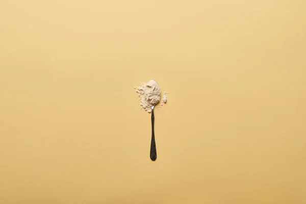 Top view of spoon with scattered flour on yellow background — Stock Photo