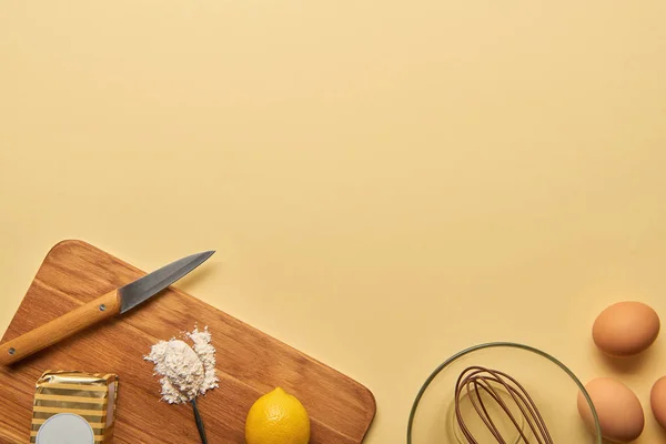 Vista superior de ingredientes y cuchillo sobre tabla de cortar de madera sobre fondo amarillo - foto de stock